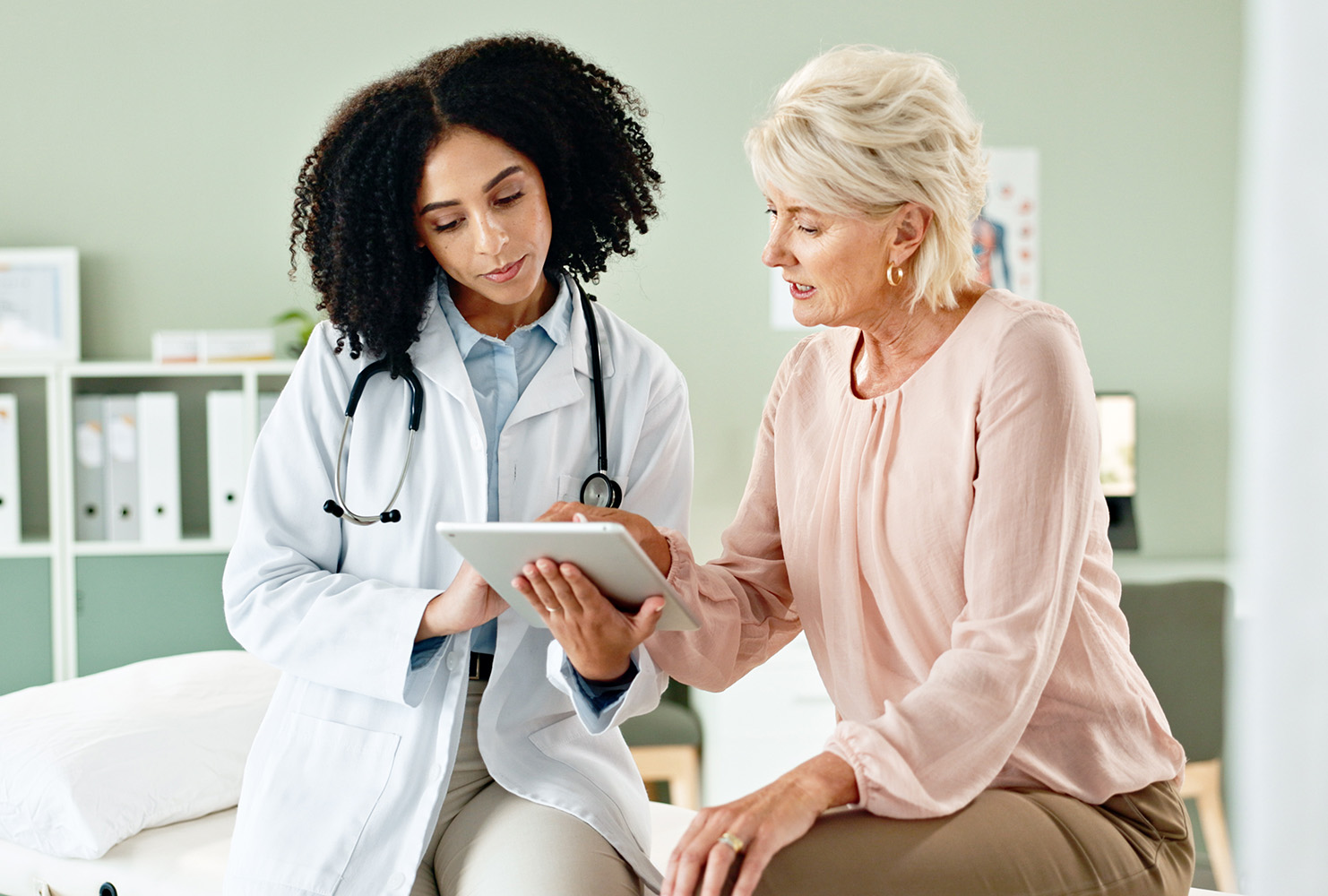 Healthcare provider reviewing information on a tablet with an older adult patient.