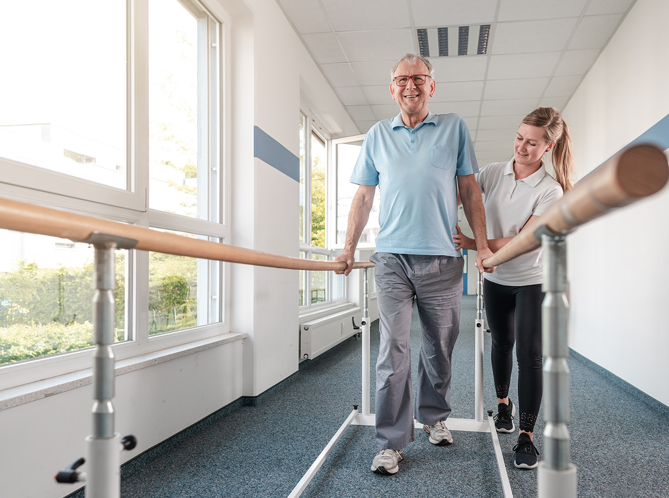 Older adult participating in physical therapy with assistance from a rehabilitation specialist.